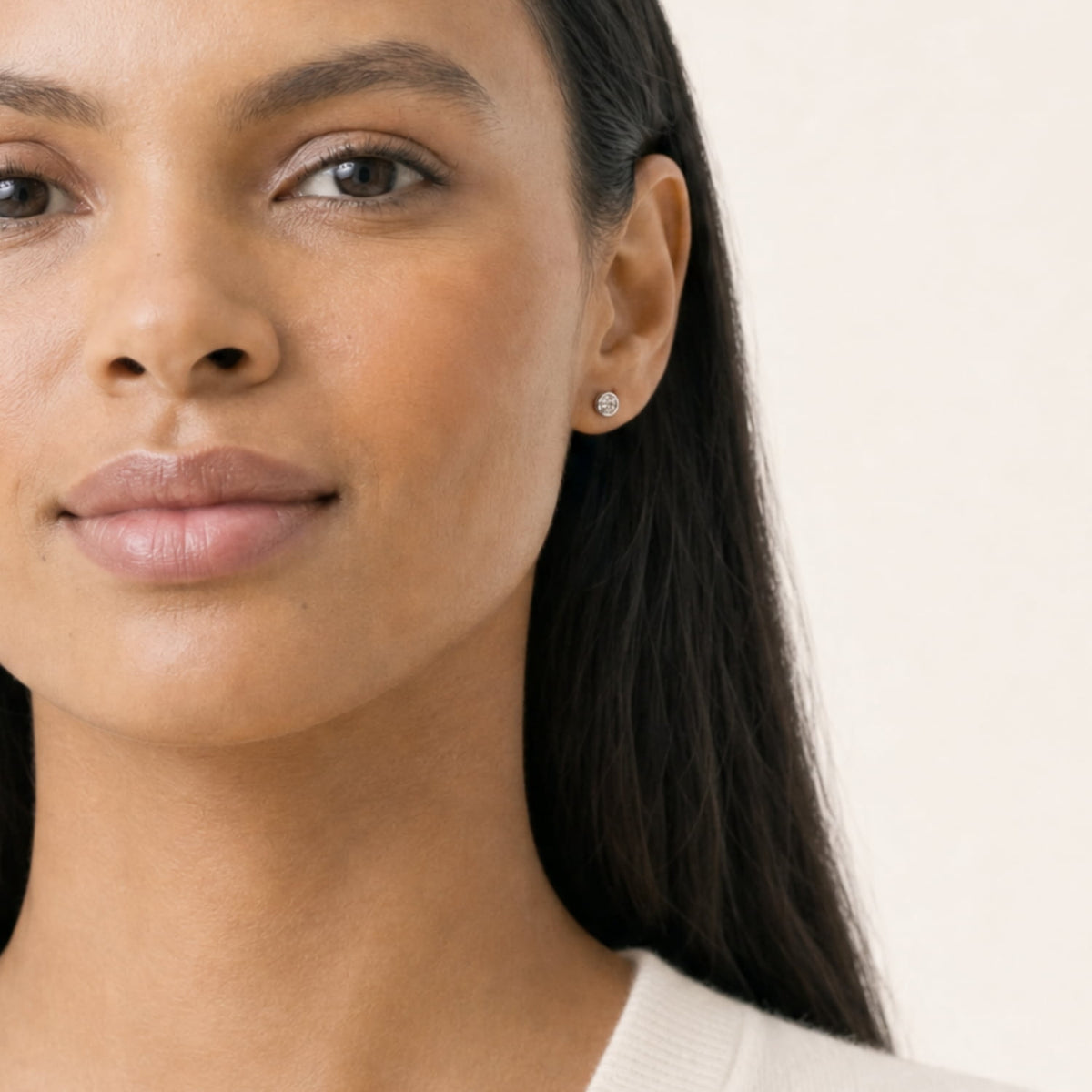 Model wears sterling silver solitaire stud earrings with lab grown diamonds set in sleek bezel settings, offering a refined and timeless design.