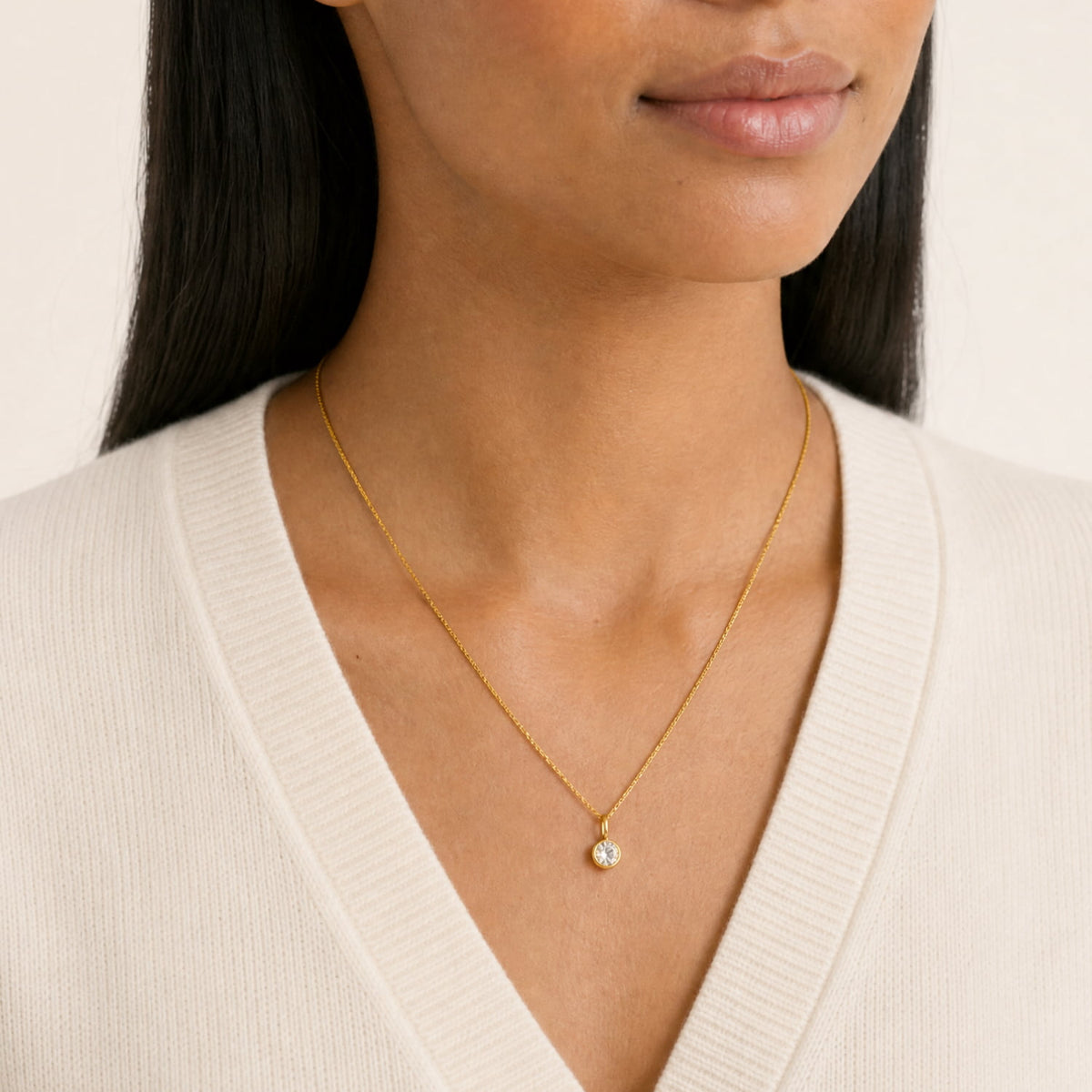 Close up of model wearing an elegant gold vermeil pendant necklace featuring a single 0.25 carat lab grown diamond in a bezel setting on a fine chain, embodying refined simplicity.