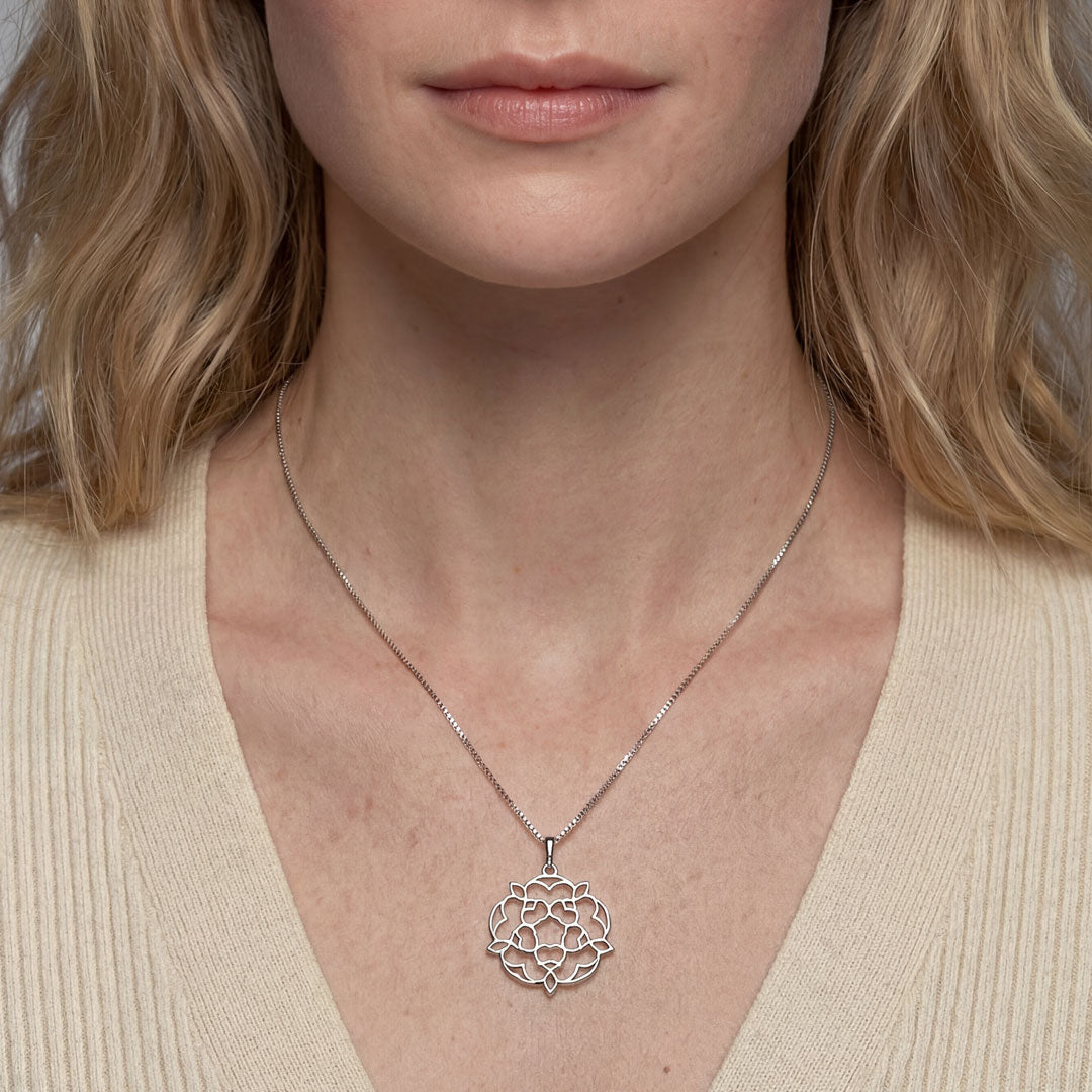 Sterling silver pendant featuring an openwork Yorkshire rose design suspended from a fine chain, blending sculptural elegance with refined contemporary silver jewellery style.
