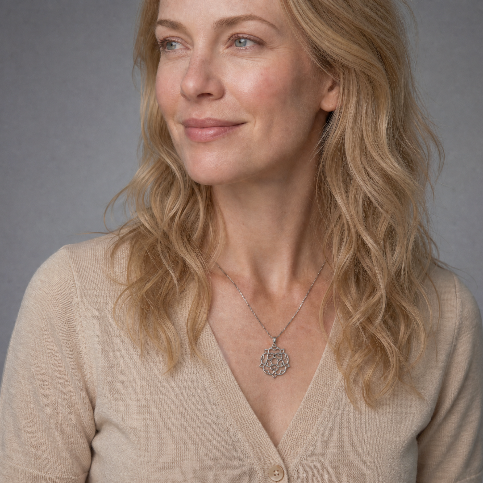 Woman with long blonde hair wears penwork sterling silver pendant in a large Yorkshire rose design, suspended from a delicate chain.