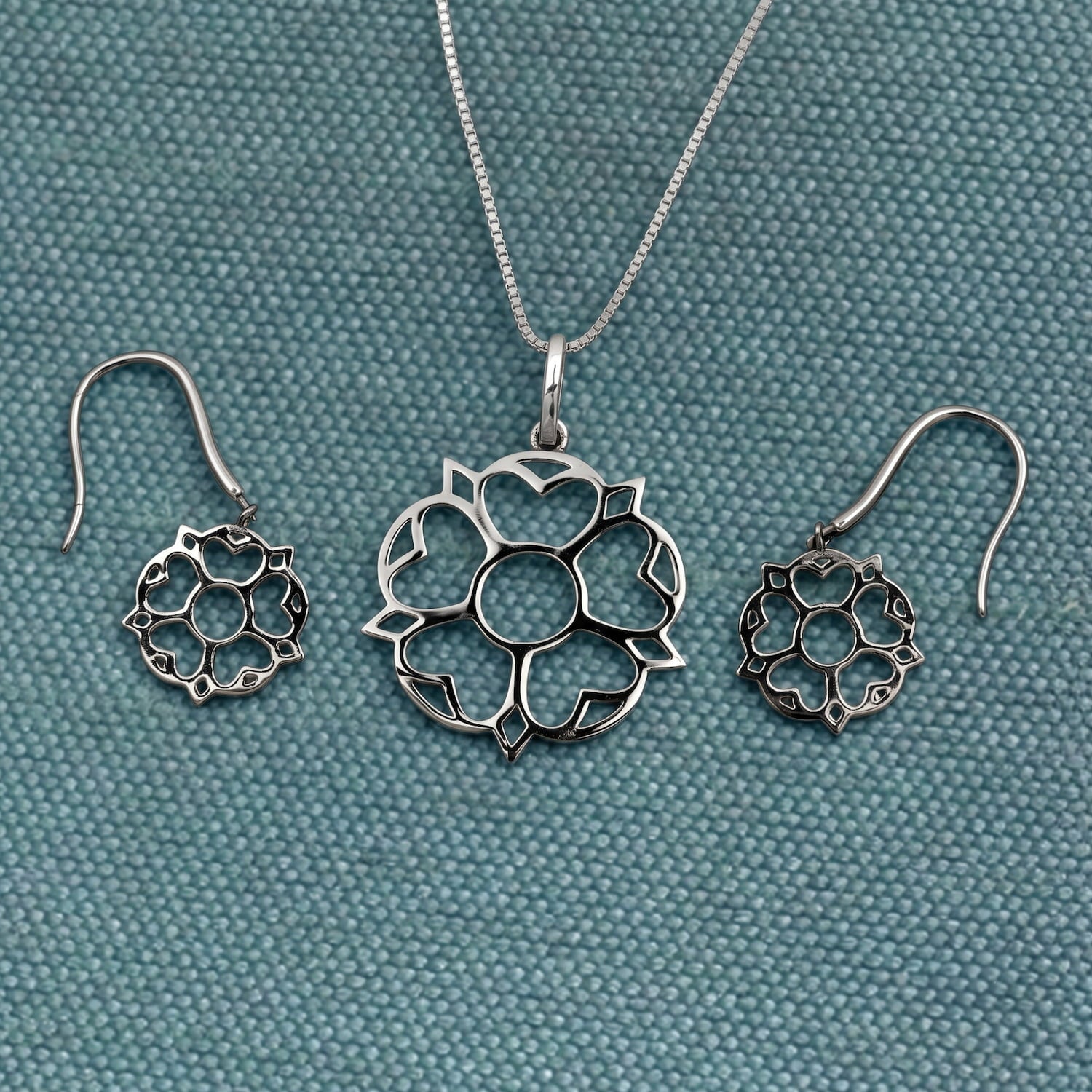 Set of sterling silver jewellery featuring Yorkshire rose-inspired drop earrings and matching pendant with smooth, sculptural petals and polished finish.