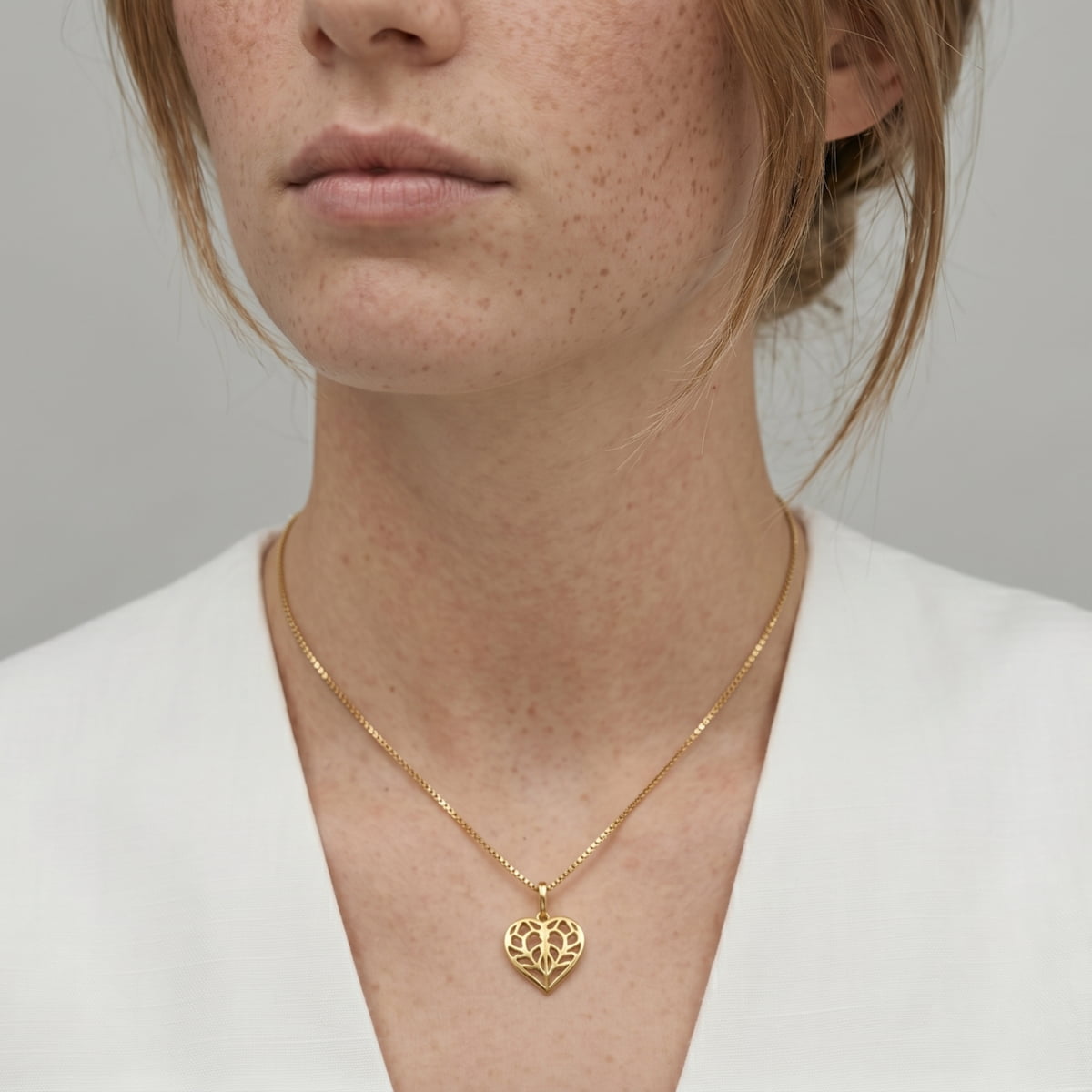 Delicate gold vermeil necklace featuring a miniature openwork heart pendant inspired by Yorkshire, suspended on a fine chain, styled with a neutral white top.