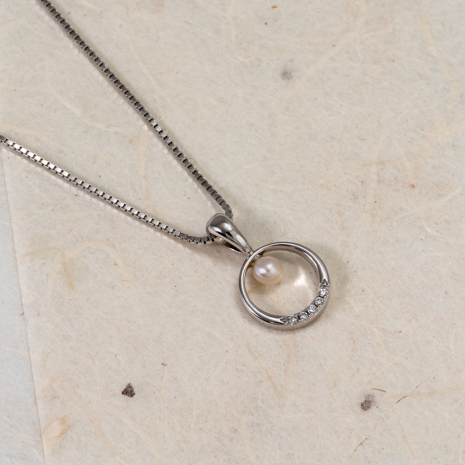 Sterling silver necklace featuring a circular pendant with a freshwater pearl and a row of lab grown diamonds, showcasing elegant and refined contemporary design.
