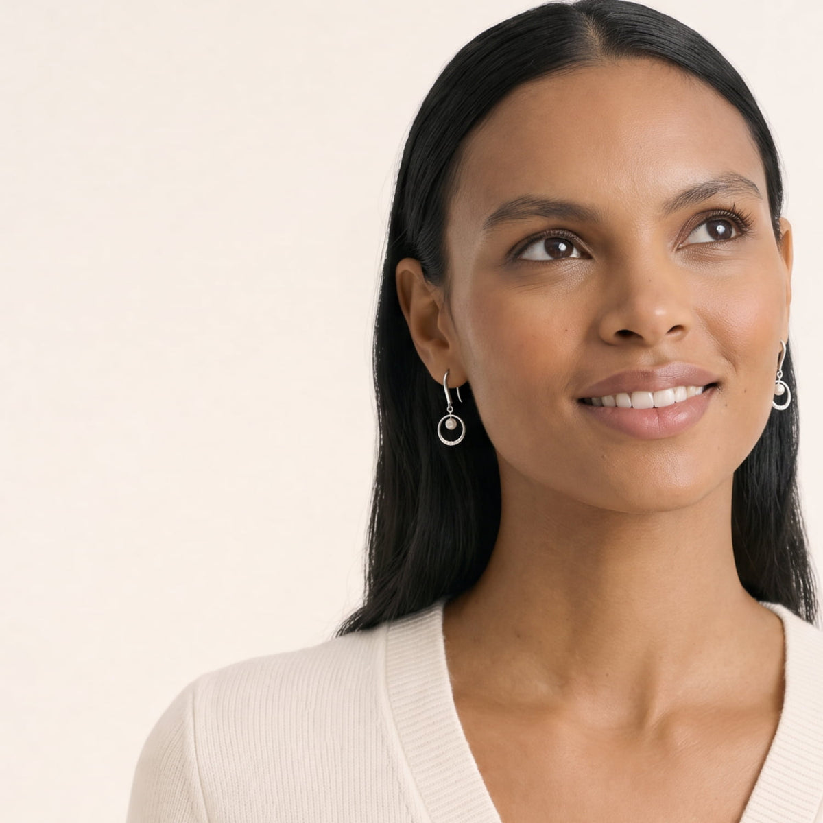 Model wears elegant sterling silver drop earrings featuring a polished circle frame accented with freshwater pearls and a row of small lab-grown diamonds for refined sparkle.