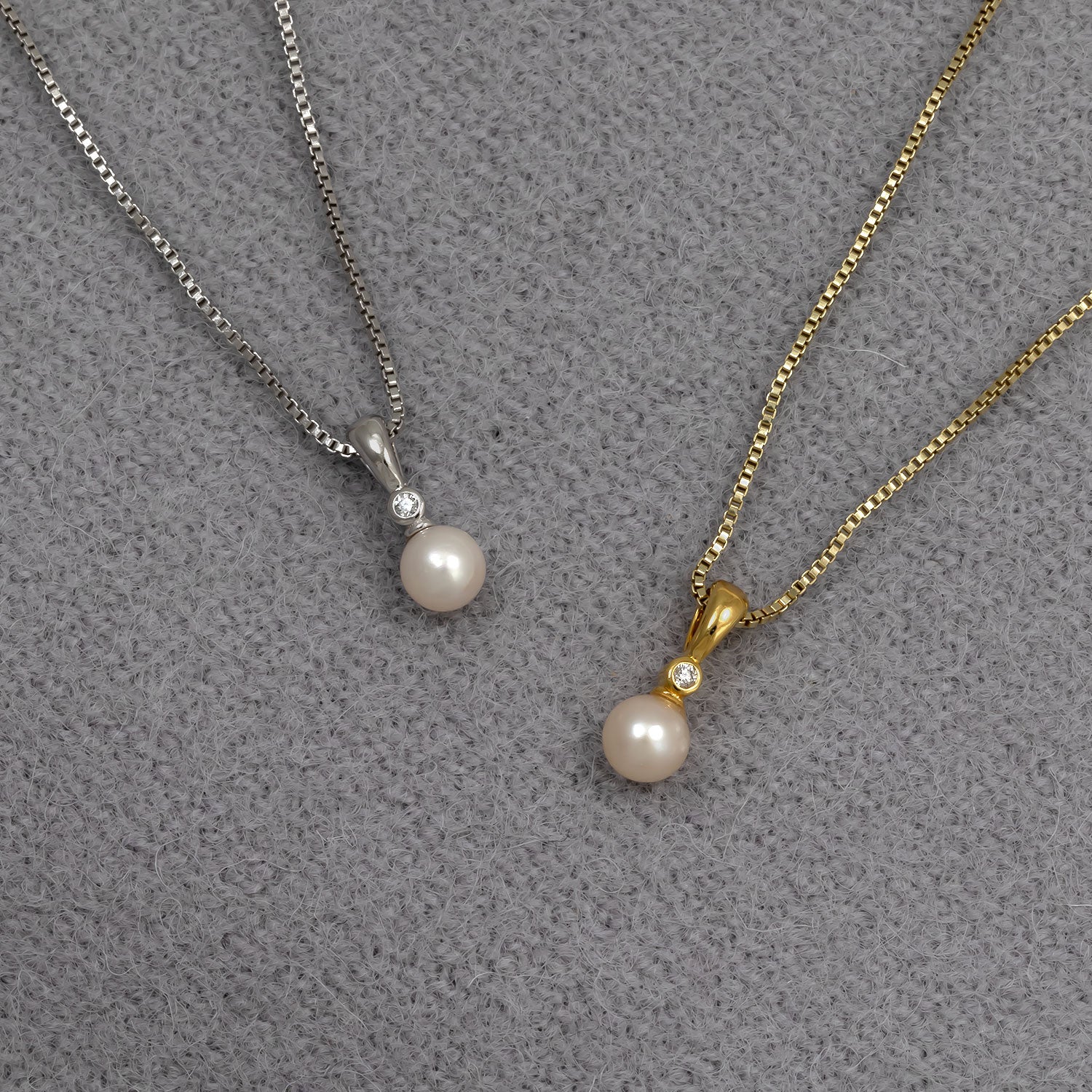 Two elegant pendant necklaces featuring freshwater pearls and small lab grown diamonds, one in sterling silver and the other in gold vermeil, displayed on a textured grey background.