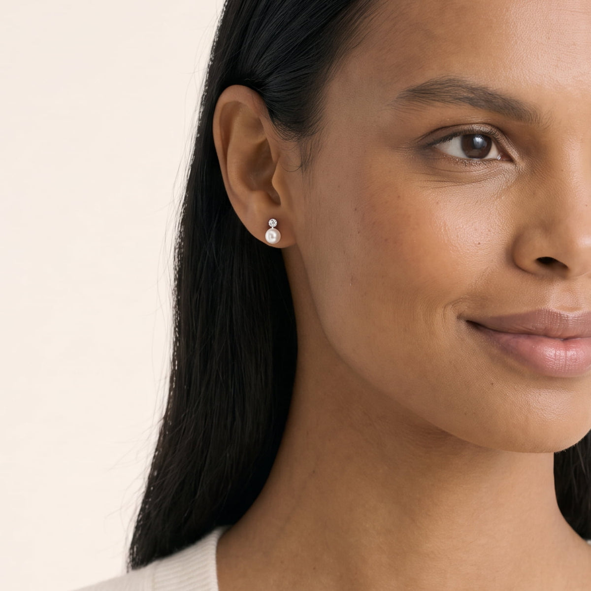 Model wears a pair of sterling silver stud earrings featuring round freshwater pearls accented with small lab grown diamonds set above, showcasing a refined and elegant design.