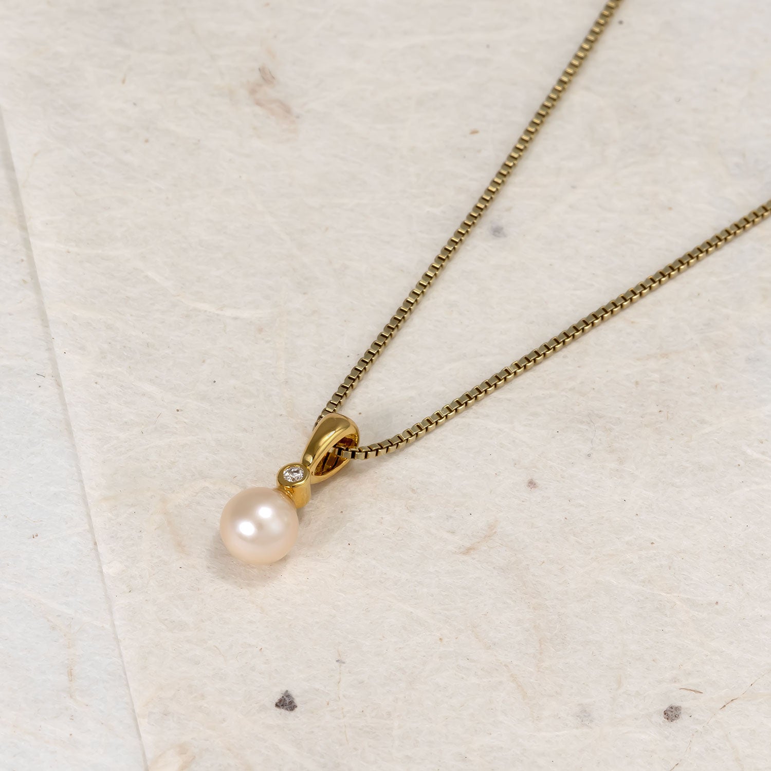 Elegant gold vermeil pendant necklace featuring a single freshwater pearl and a small lab grown diamond accent on a fine chain, embodying refined contemporary design.