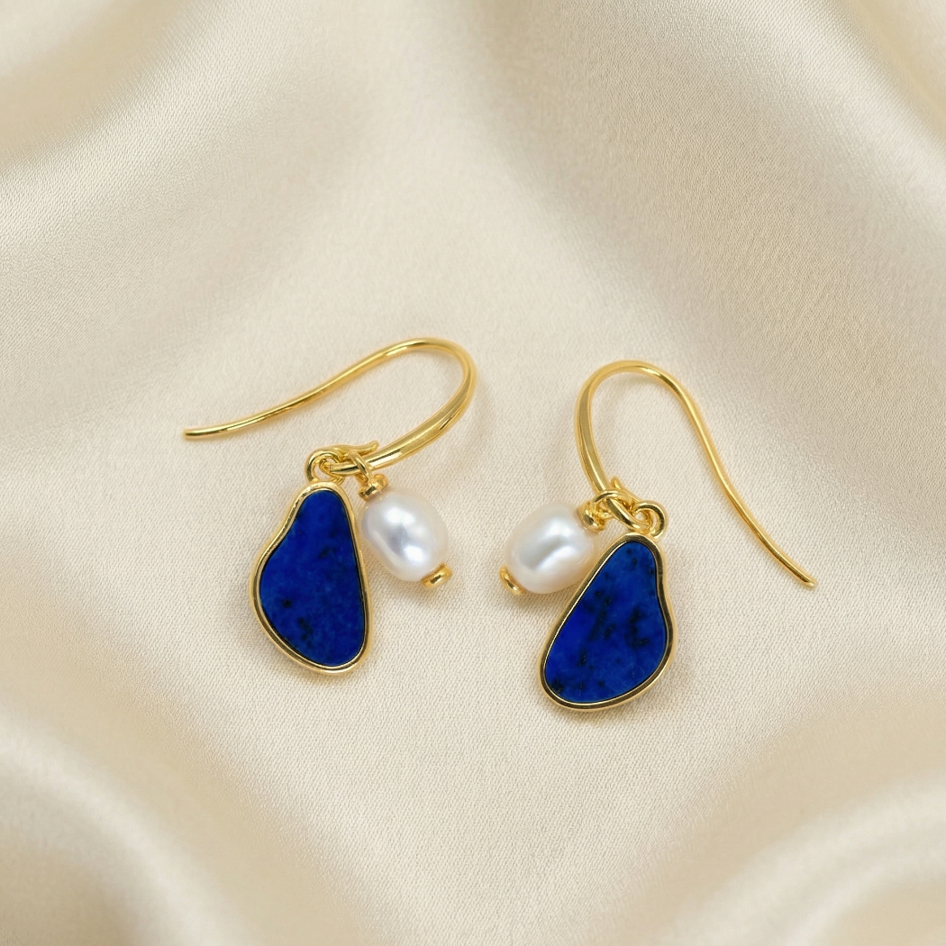 Pair of gold vermeil drop earrings featuring irregular baroque pearls and deep blue lapis lazuli stones set in elegant, sculptural sterling silver frames.