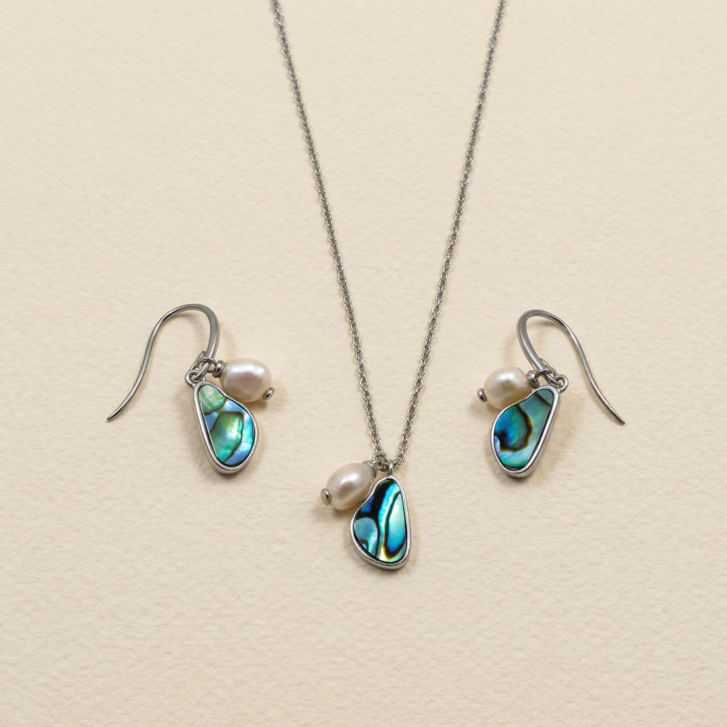 Sterling silver drop earrings and matching pendant featuring irregular baroque pearls and vibrant abalone shell in sculptural settings, displayed on a neutral background.