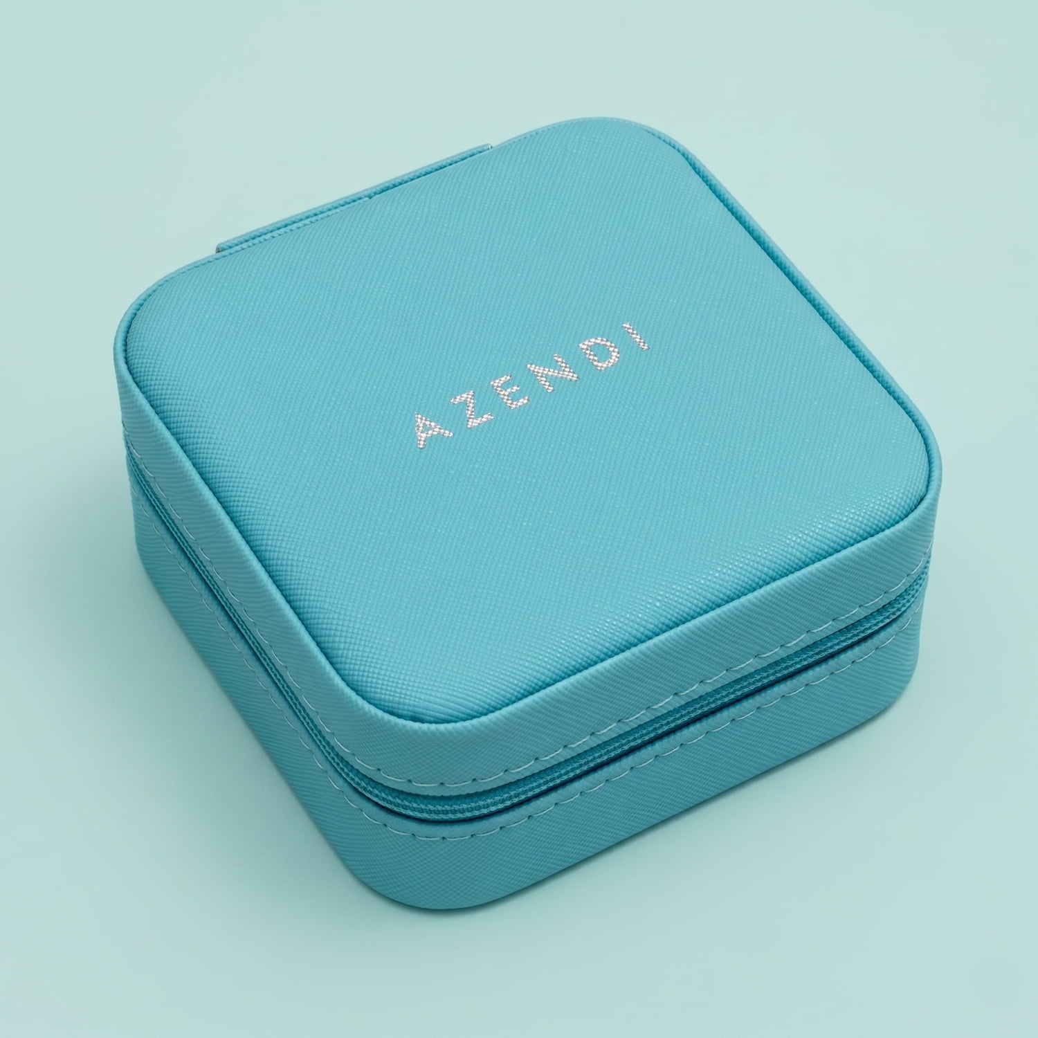 Turquoise jewellery box with 'AZENDI' branding on a light blue background