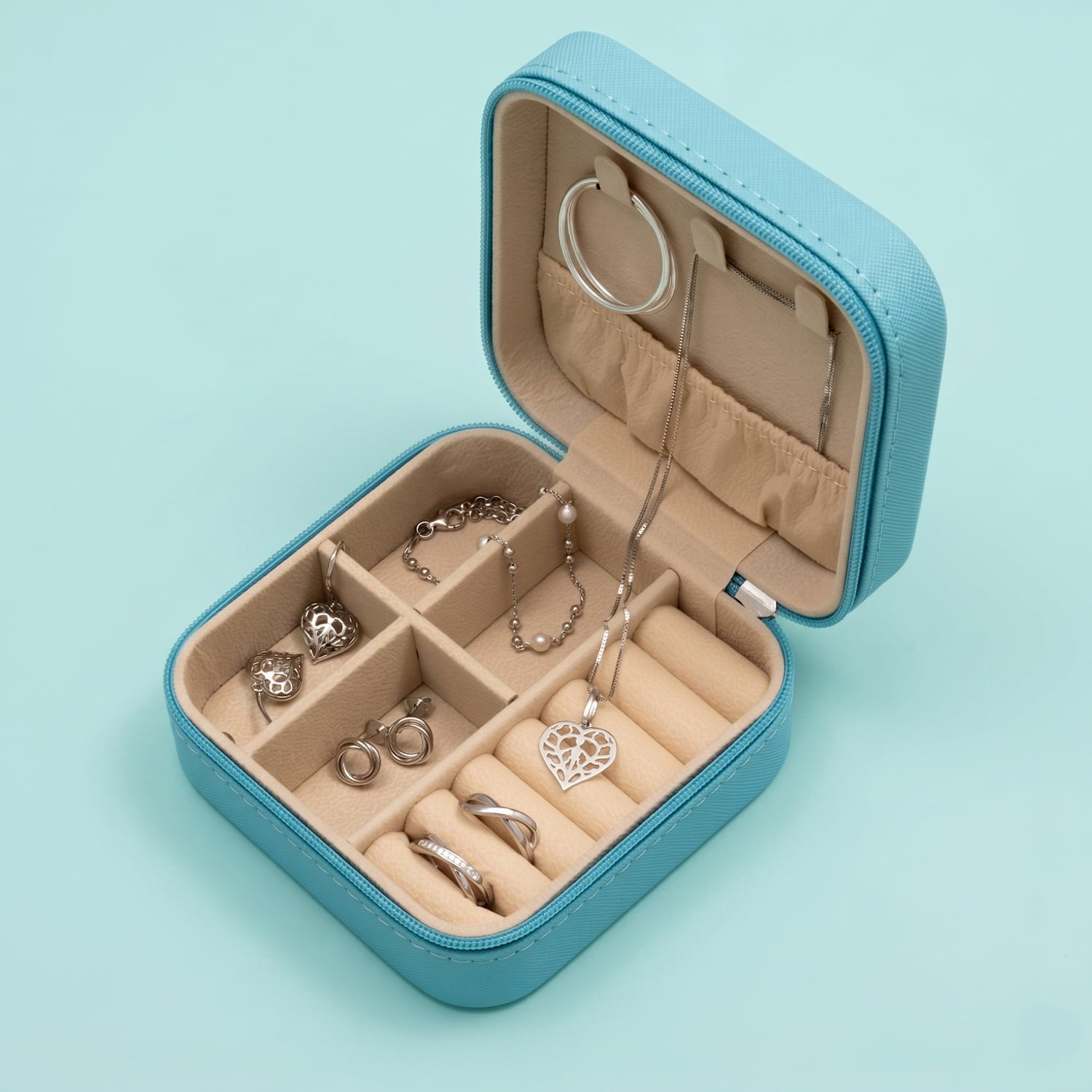 Open turquoise jewellery box with jewellery on a light turquoise background