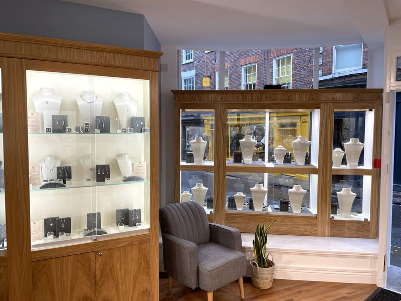 Display cases inside Azendi York with decorative items in a room with a gray armchair and a window view.