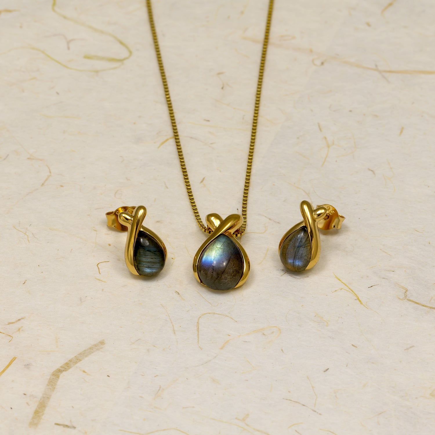 Gold vermeil earrings and matching pendant featuring teardrop-shaped spectrolite gemstones embraced by smooth, sculptural gold frames for a refined and contemporary look.