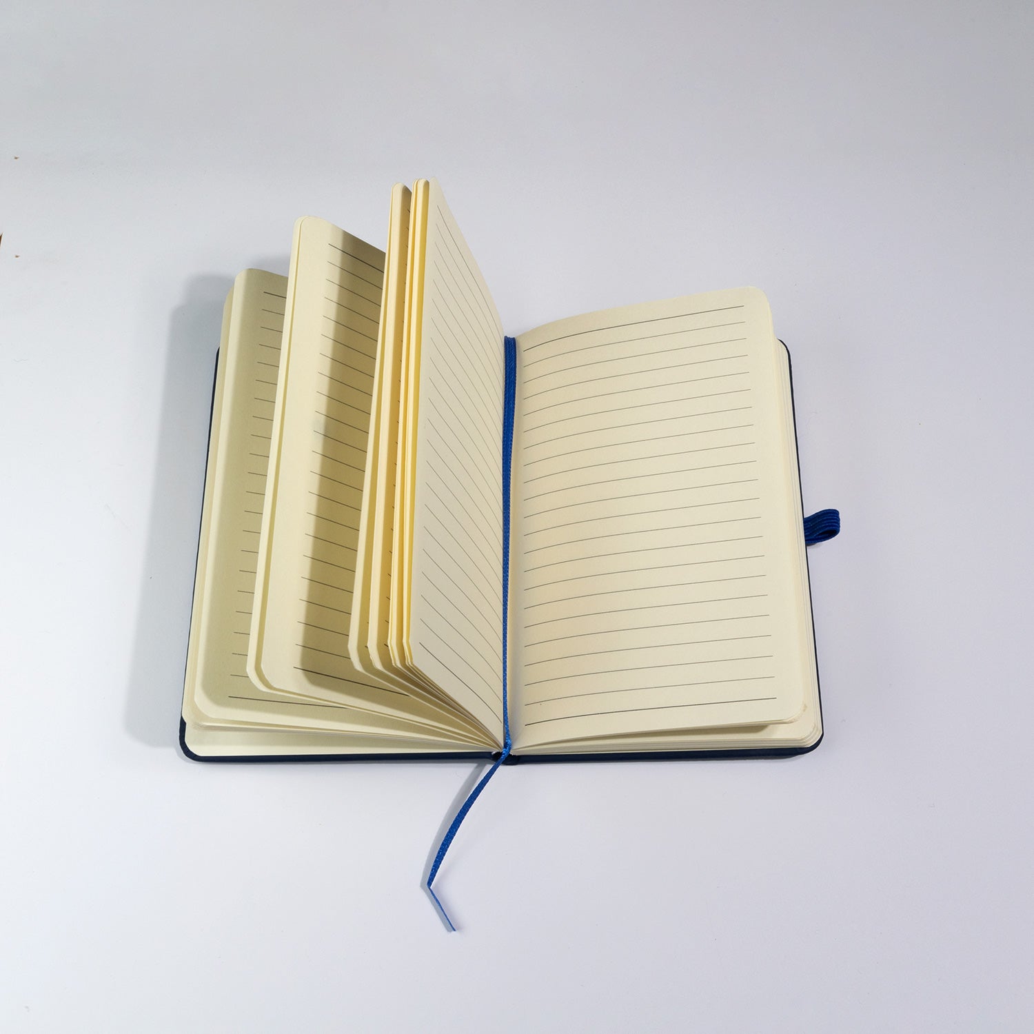 Open A6-sized notebook with cream-colored lined pages and a blue fabric bookmark ribbon, designed for note-taking and journaling.