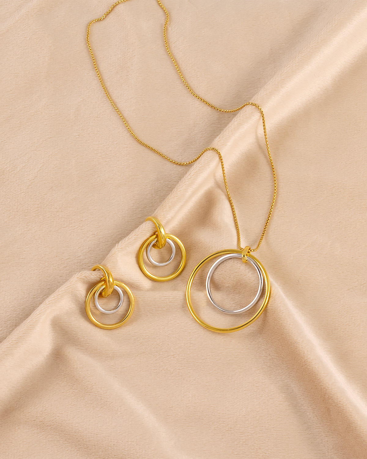 Contemporary silver and gold vermeil hoop earrings and matching pendant necklace featuring nested circular designs, showcasing sculptural elegance and modern craftsmanship.