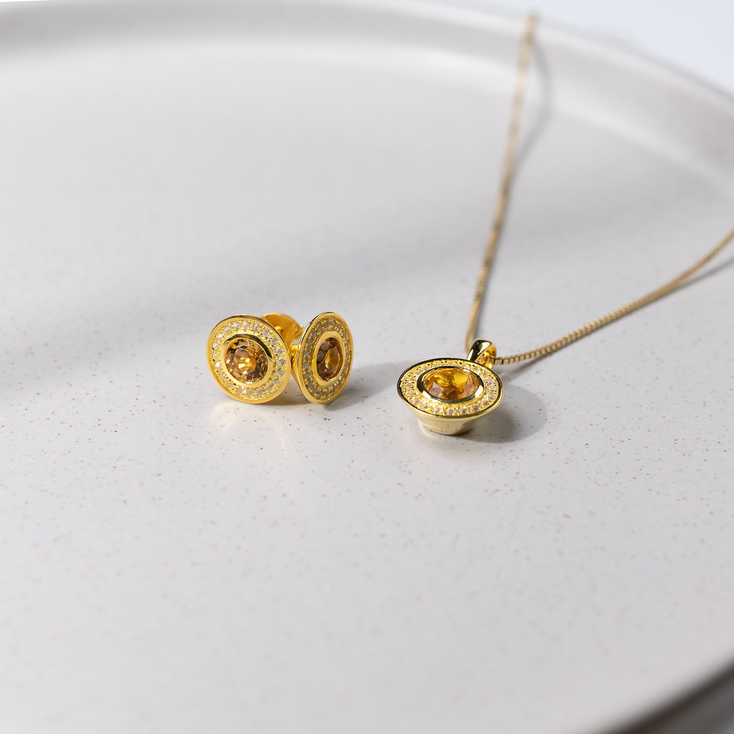 Pair of yellow gold vermeil earrings and matching pendant featuring oval citrine centers surrounded by white topaz accents, offering a refined sculptural look.