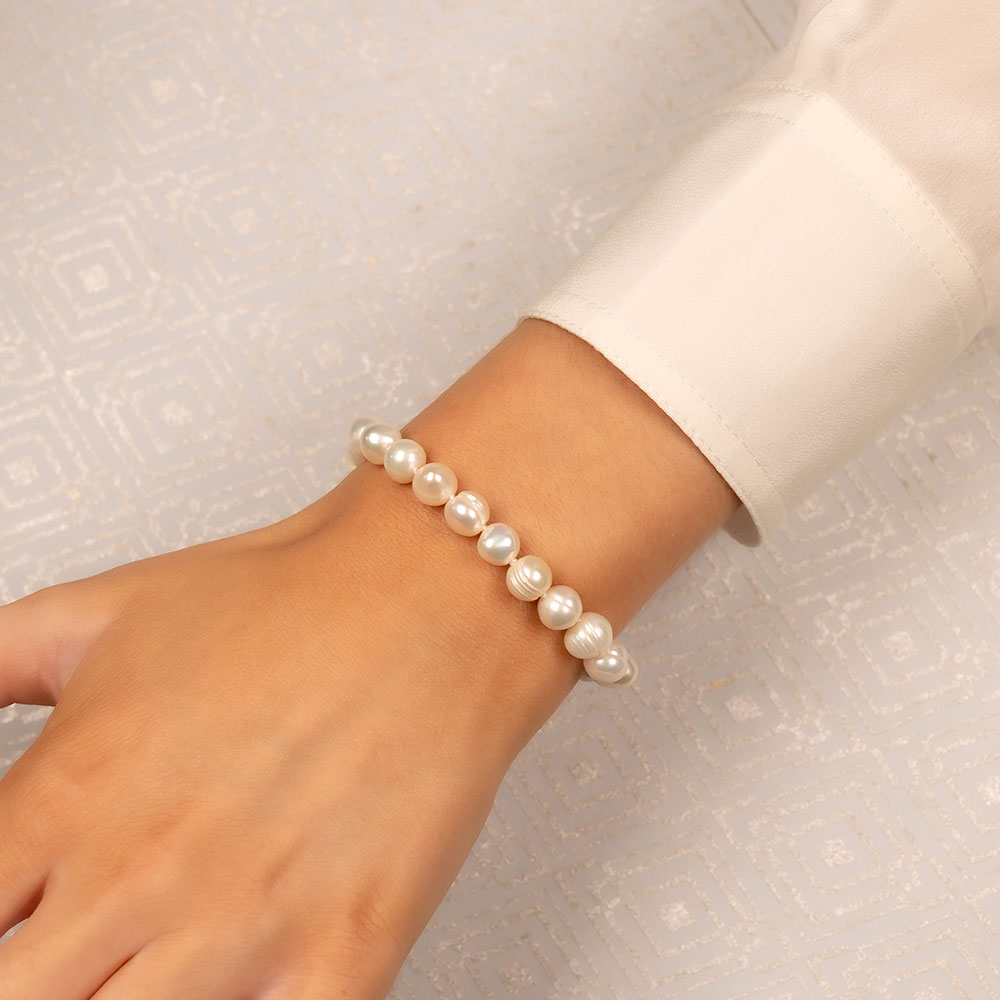Close-up of a wrist wearing a delicate freshwater pearl bracelet featuring lustrous 8mm pearls, highlighting a timeless and elegant design in sterling silver jewellery by Azendi.