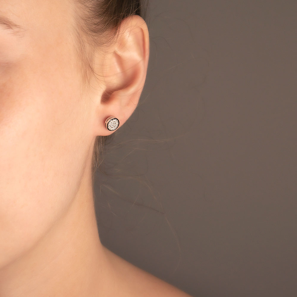 Close-up of an ear wearing a sterling silver pavé disc stud earring, featuring a sculptural design with sparkling stone accents for a refined and contemporary look.
