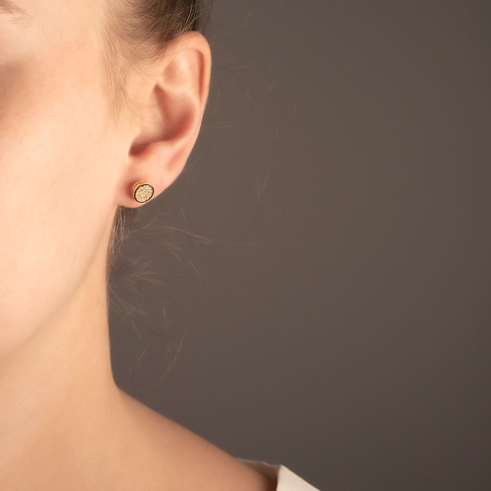 Close-up of an ear wearing a sterling silver stud earring featuring a pavé-set disc design with sparkling stones, highlighting a sculptural and refined look by Azendi.