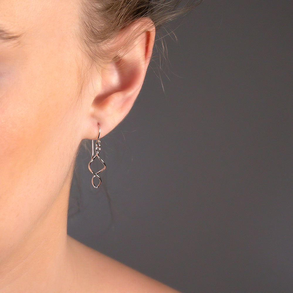 Elegant sterling silver drop earring featuring a flowing twisted design, suspended from a delicate hook for a modern and sculptural jewellery statement.