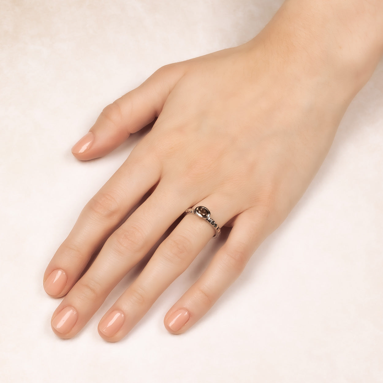 A sterling silver ring with a faceted smoky quartz gemstone set in the center, featuring a textured hammered effect on the band.
