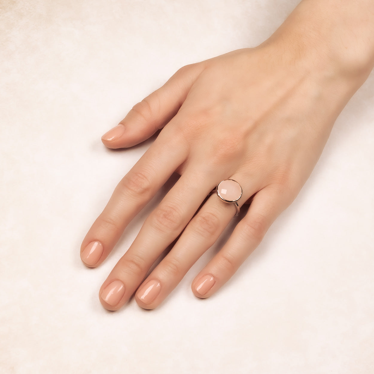 Hand wearing a polished sterling silver ring featuring a smooth, round rose quartz stone, showcasing a refined and contemporary design in silver jewellery.