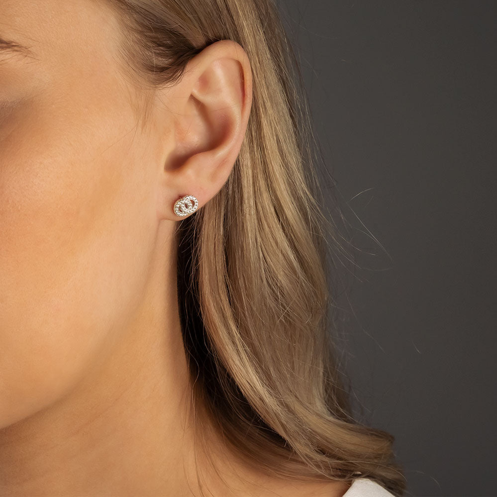 Close-up of an ear adorned with sterling silver stud earrings featuring interlocking circles set with sparkling cubic zirconia, showcasing a modern and elegant silver jewellery design.