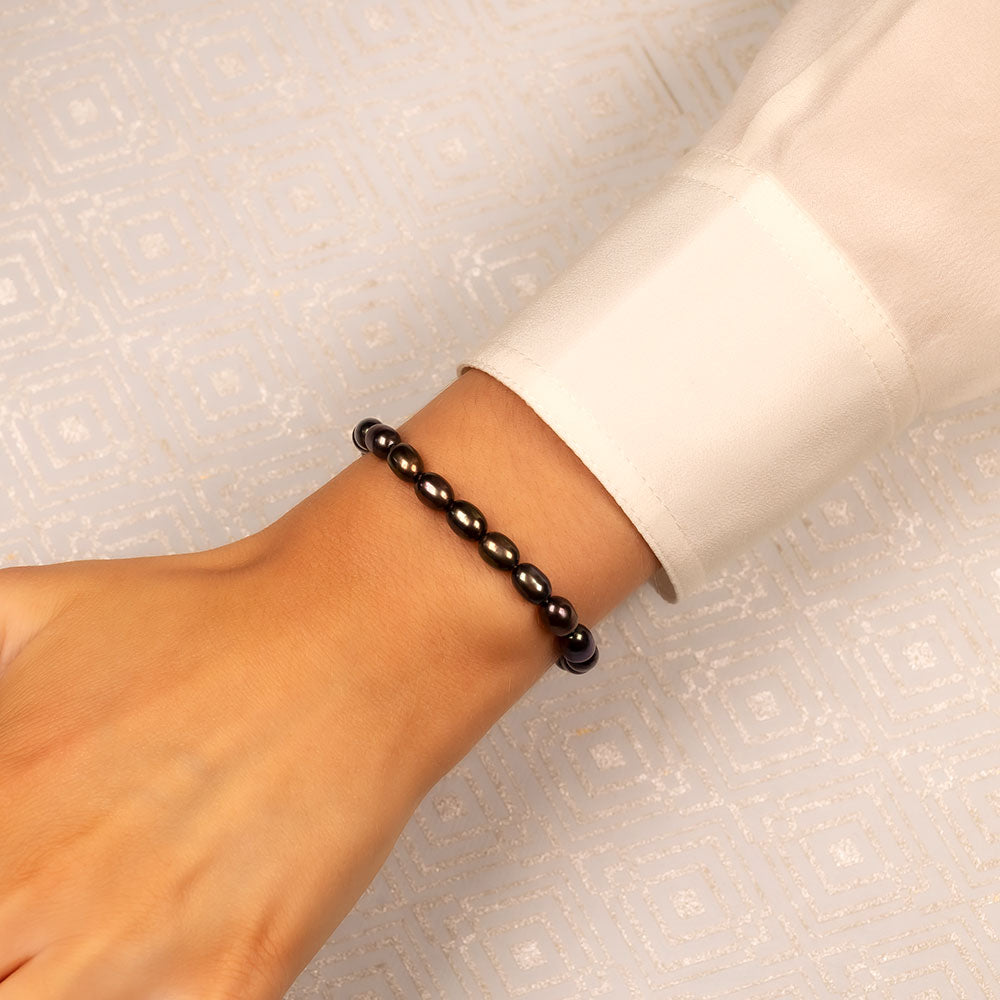 Close-up of a wrist wearing a stretch bracelet featuring lustrous dark freshwater pearls, highlighting elegant and sculptural sterling silver jewellery design by Azendi.
