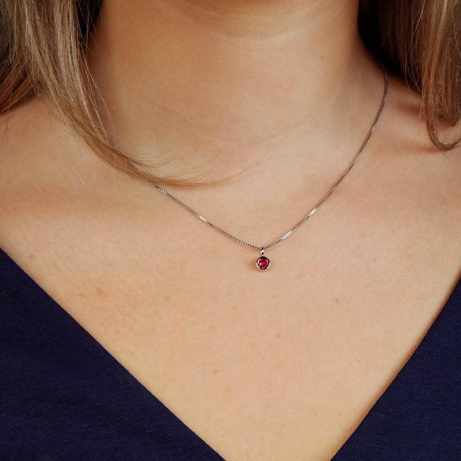 Delicate sterling silver pendant featuring a bezel-set ruby gemstone suspended on a fine chain, exemplifying refined British craftsmanship and contemporary design.