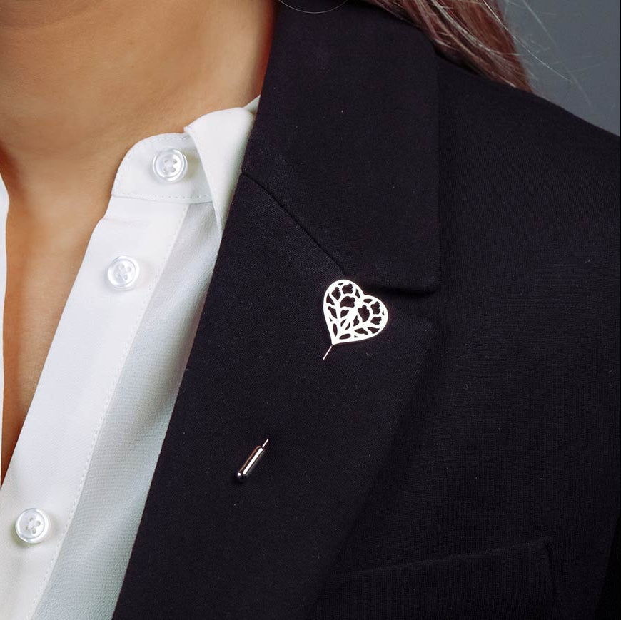 Sterling silver lapel pin shaped as an openwork heart inspired by Yorkshire, styled on a black blazer over a white shirt, showcasing expert British silver craftsmanship.