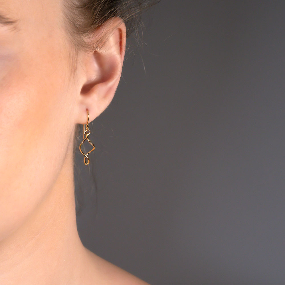 Close-up of a woman's ear wearing a Simple Twist Drop Earring - Yellow Gold Vermeil, featuring a delicate twisted design in gold vermeil, approximately 3.2cm long.