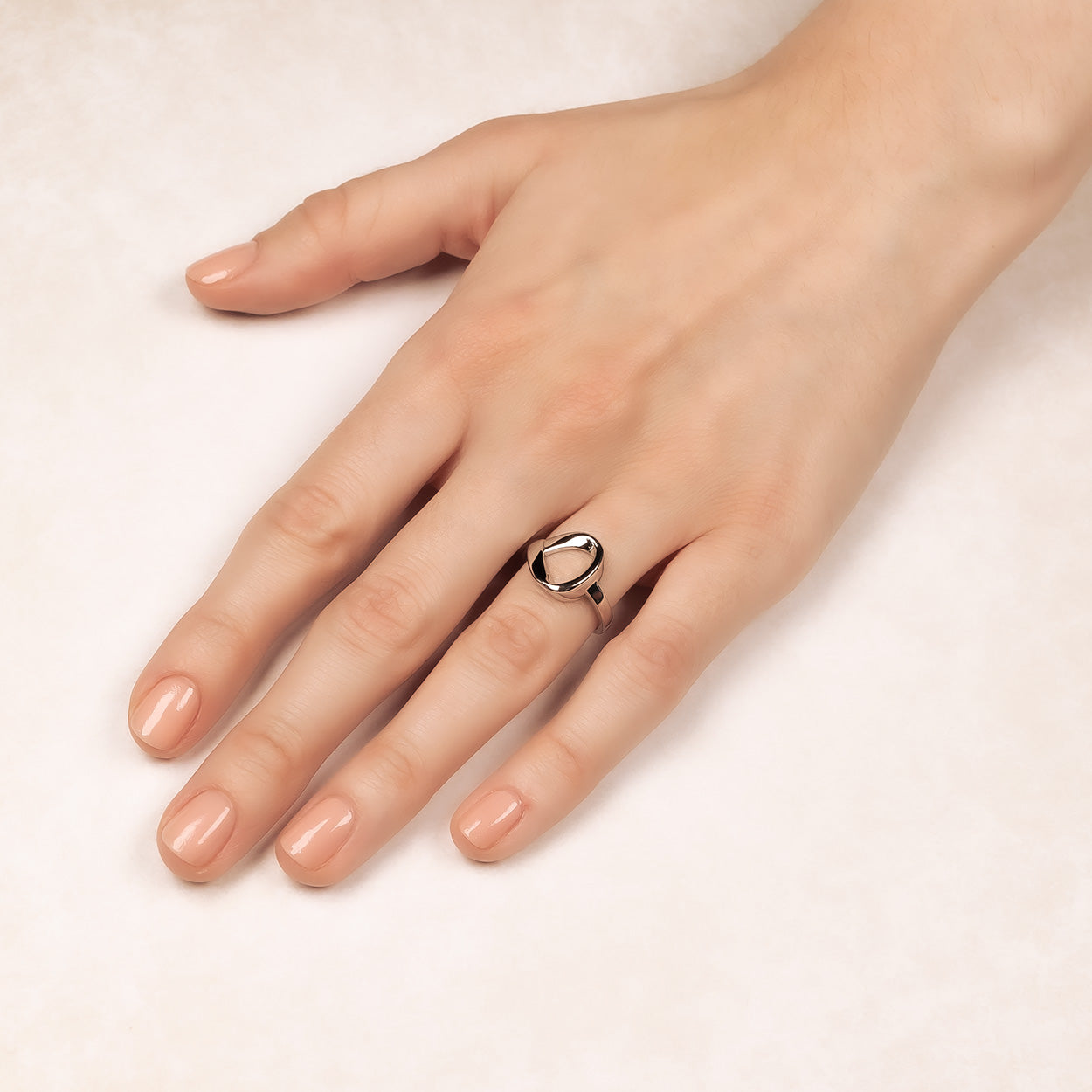Hand wearing a polished sterling silver ring featuring a sculptural ribbon loop design with a smooth band, exemplifying elegant contemporary silver jewellery by Azendi.