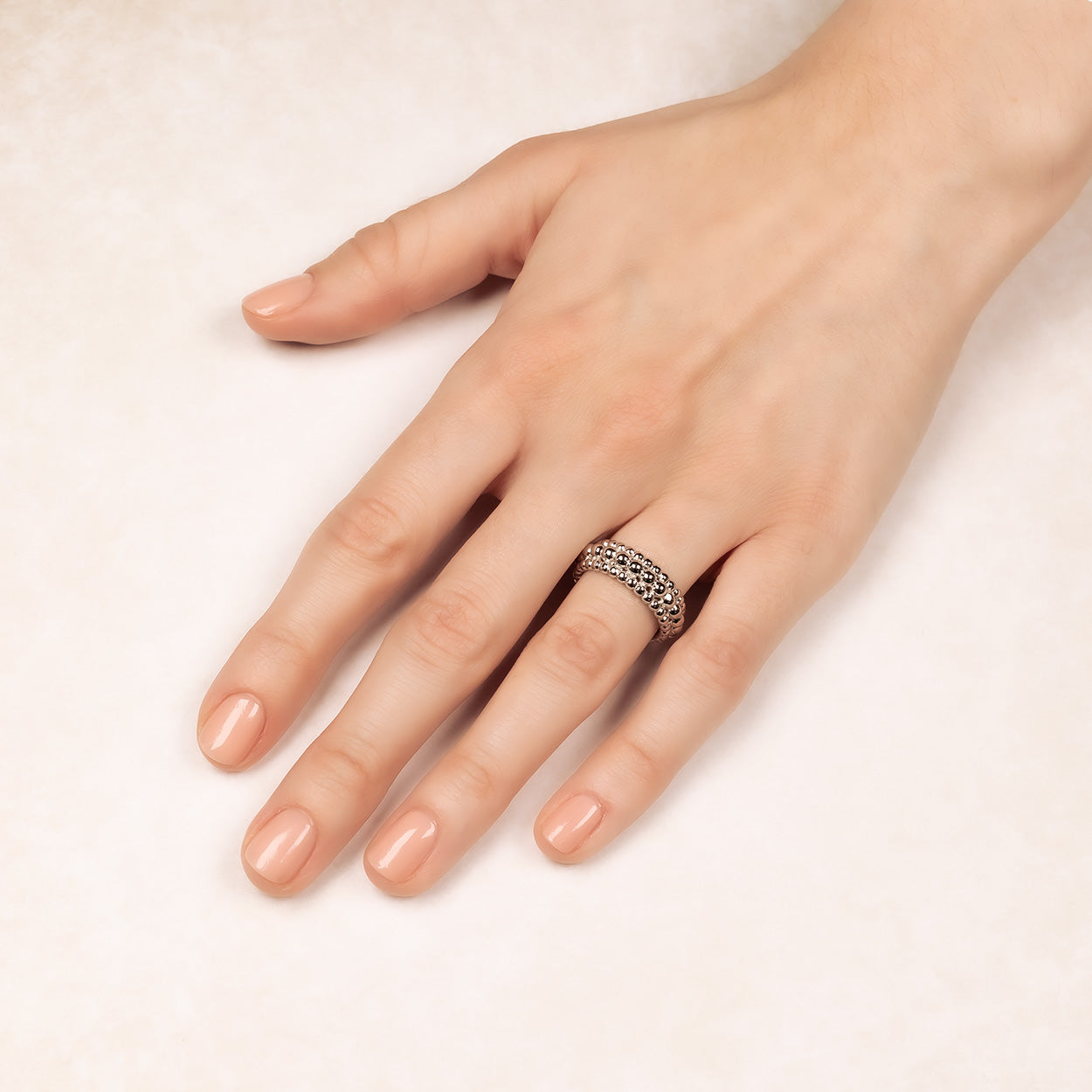 Sterling silver ring featuring three beaded bands fused together, creating a sculptural and contemporary design on a model's finger, reflecting expert British jewellery style.