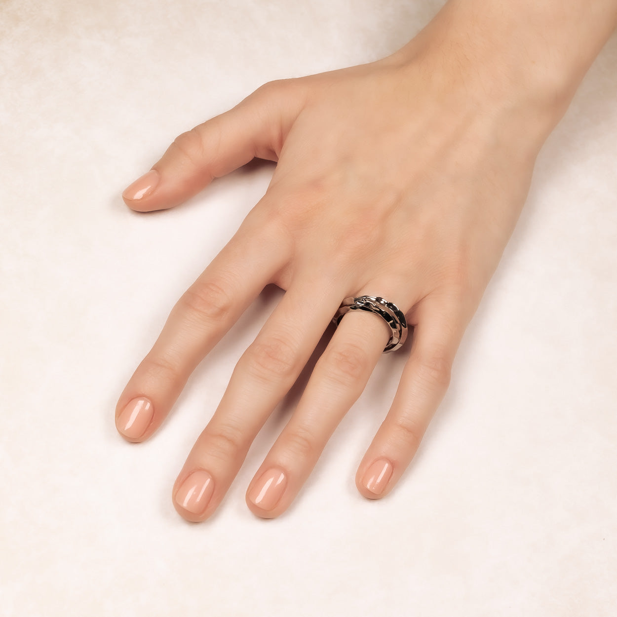 Sterling silver hammered band ring featuring a textured surface with a bold sculptural design, worn on a hand against a soft neutral background.