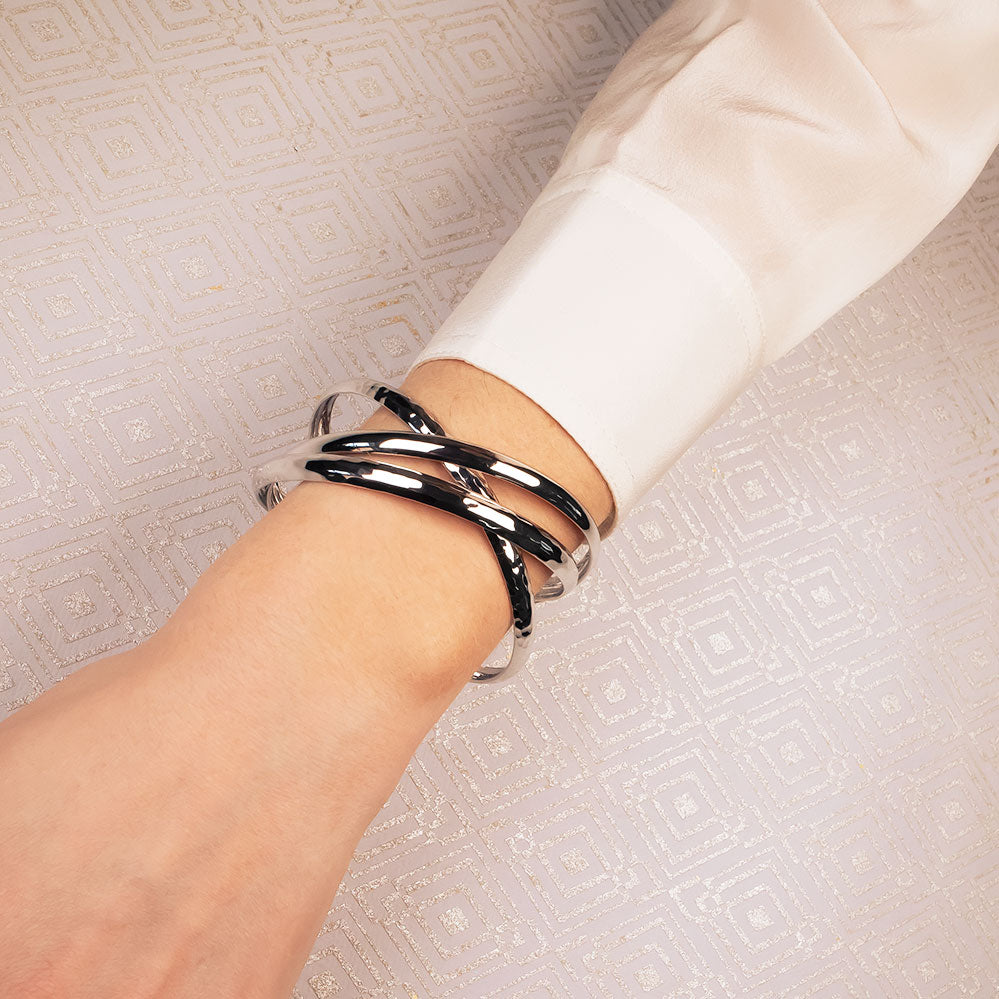 Sterling silver triple bangle featuring intertwined textured and polished bands, elegantly layered on the wrist to showcase modern British silver jewellery design.