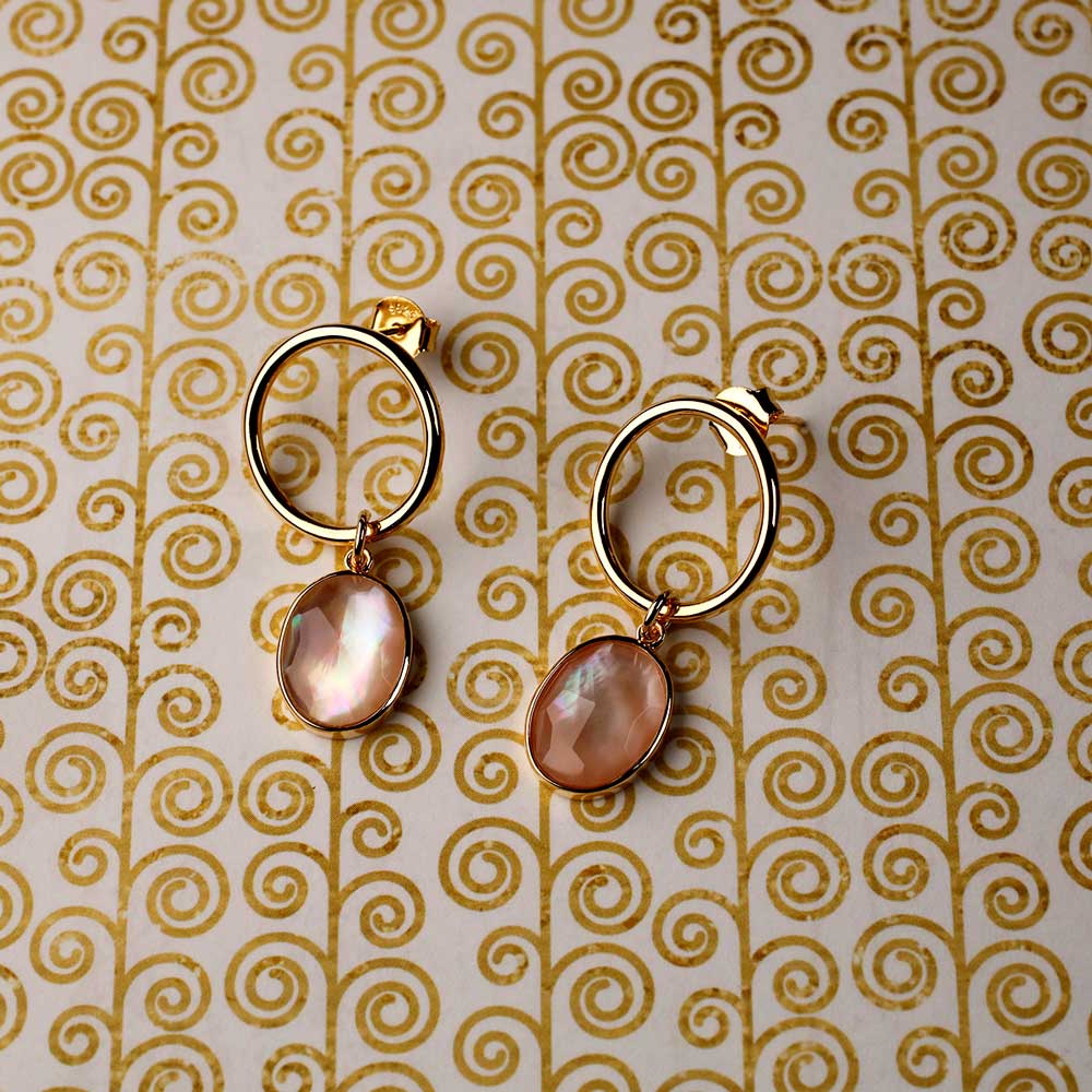 Sterling silver drop earrings featuring irregular oval mother of pearl pendants suspended from modern open oval hoops, blending sculptural design with natural iridescence.