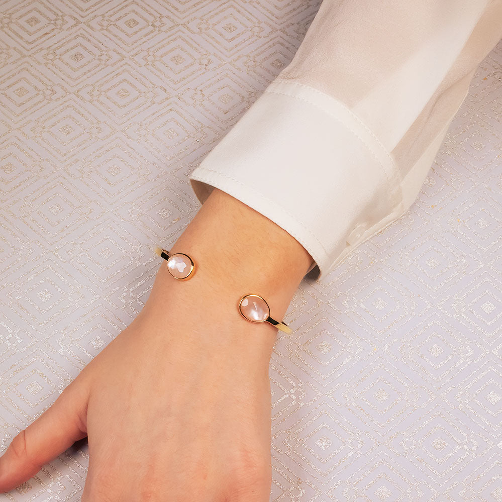 Delicate gold vermeil cuff bracelet featuring two polished mother of pearl teardrop stones at each end, worn on a wrist over a silky white blouse.