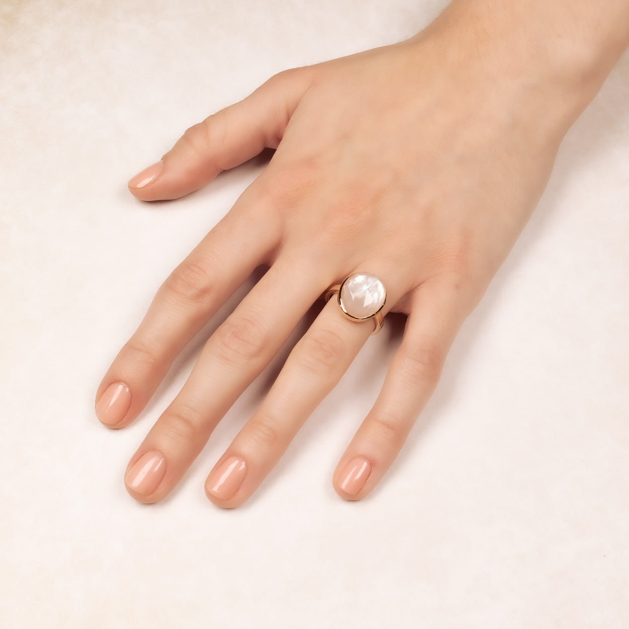 Elegant yellow gold vermeil ring featuring a smooth mother of pearl cabochon, styled on a hand with a natural manicure for a sophisticated, contemporary look.
