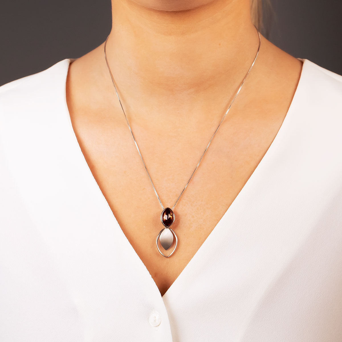 Sterling silver pendant featuring a double marquise design with a polished amber gemstone, suspended from a fine chain, showcasing refined British craftsmanship.