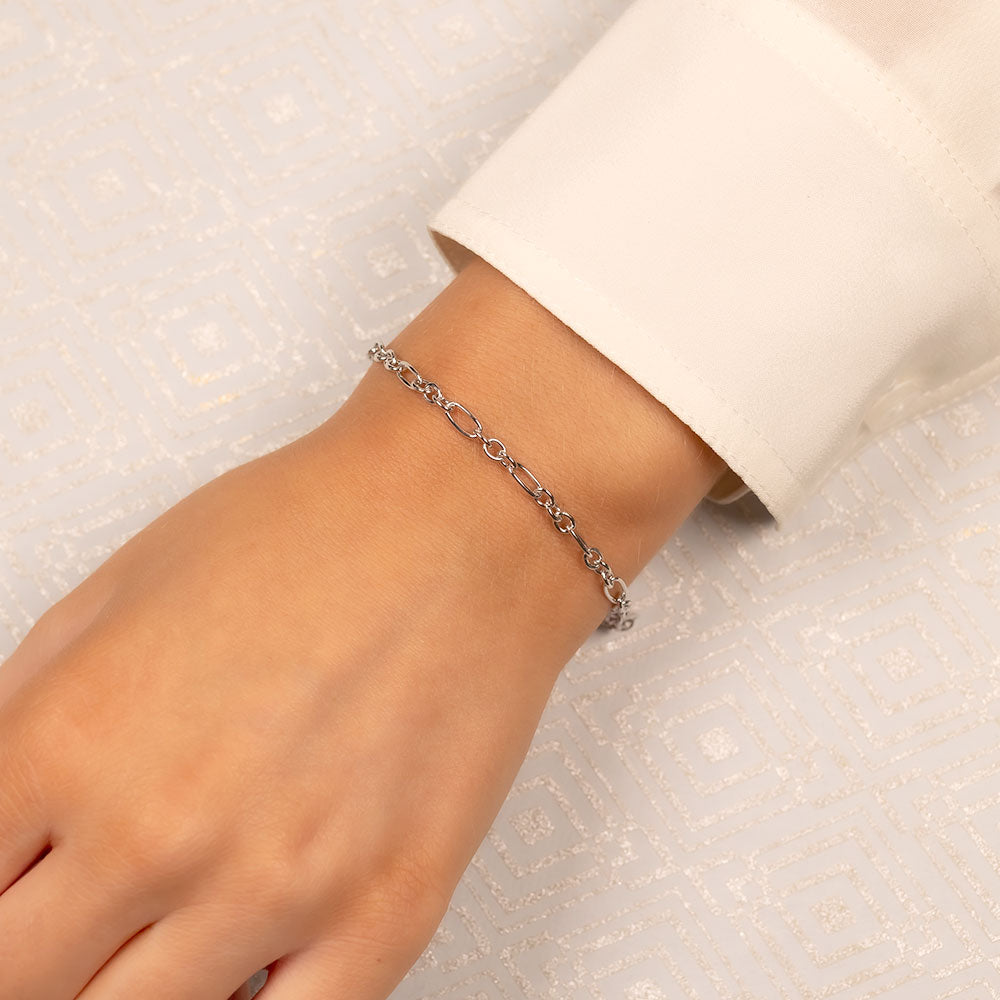 Delicate silver bracelet featuring open links with a small charm detail, showcasing modern sterling silver jewellery design with a sleek, sculptural finish.