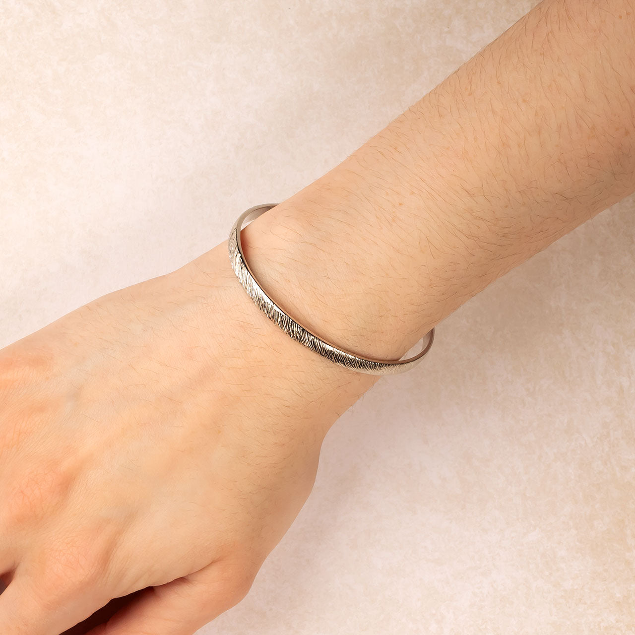 Silver bangle featuring a diagonal textured element design, worn on the wrist, showcasing a blend of sculptural detail and contemporary sterling silver craftsmanship.