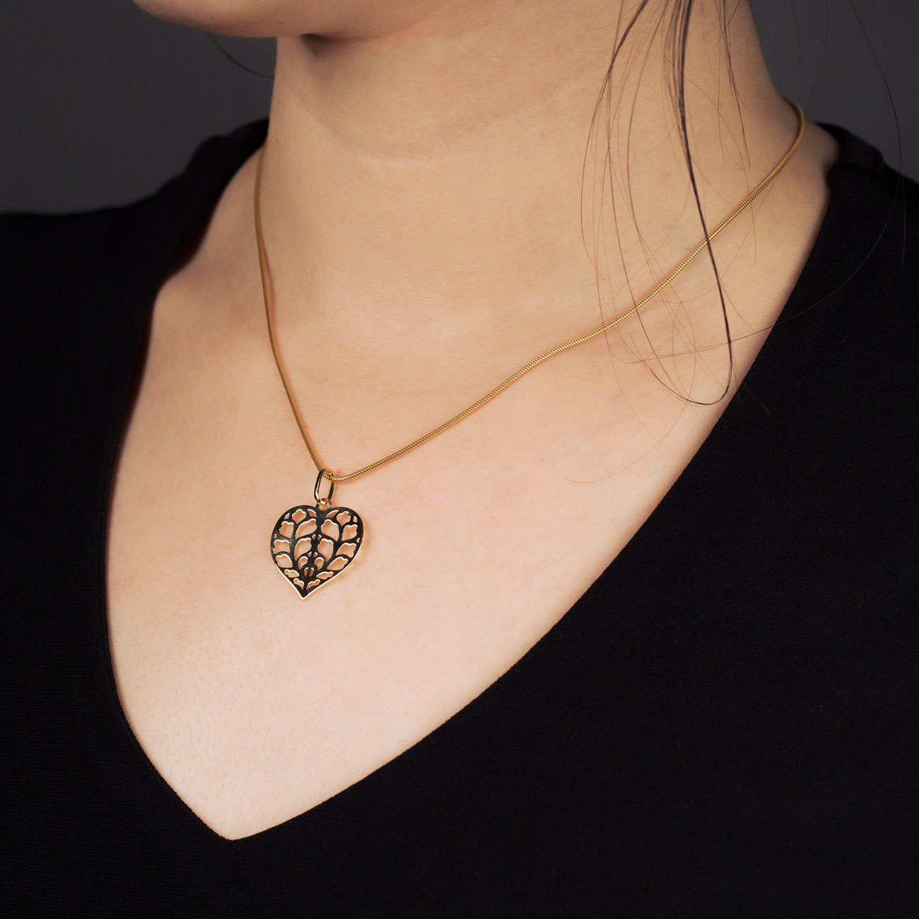 18ct yellow gold heart-shaped pendant featuring an intricate openwork Yorkshire rose pattern, suspended from a delicate, slender chain for an elegant, sculptural effect.