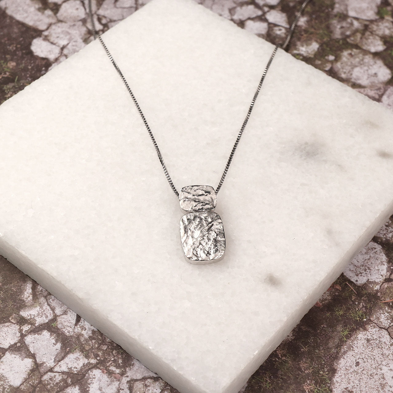 Sterling silver pendant featuring two textured rectangular elements with an organic, sculptural finish on a fine chain, embodying refined contemporary silver jewellery.