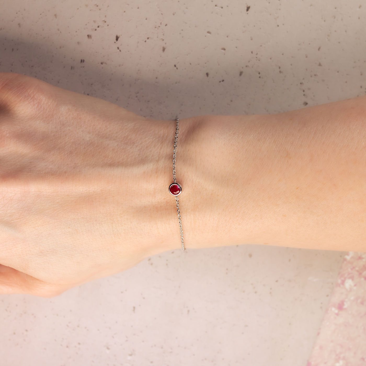Delicate sterling silver bracelet featuring a single deep red ruby birthstone, crafted with an adjustable sliding clasp for a refined and versatile design.