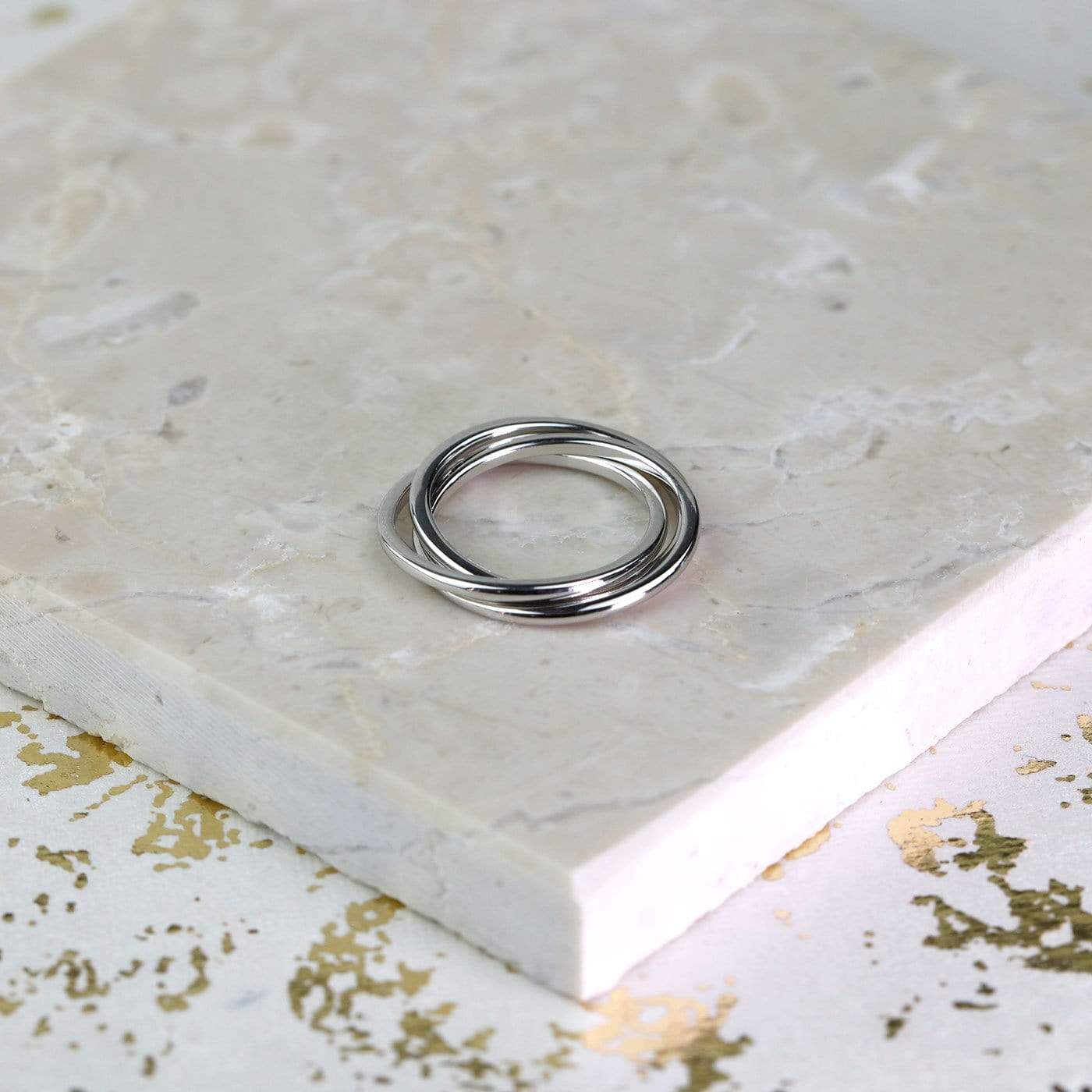 Sterling silver wedding ring featuring a sculptural interlocking band design, polished to a smooth finish for a refined contemporary jewellery piece.