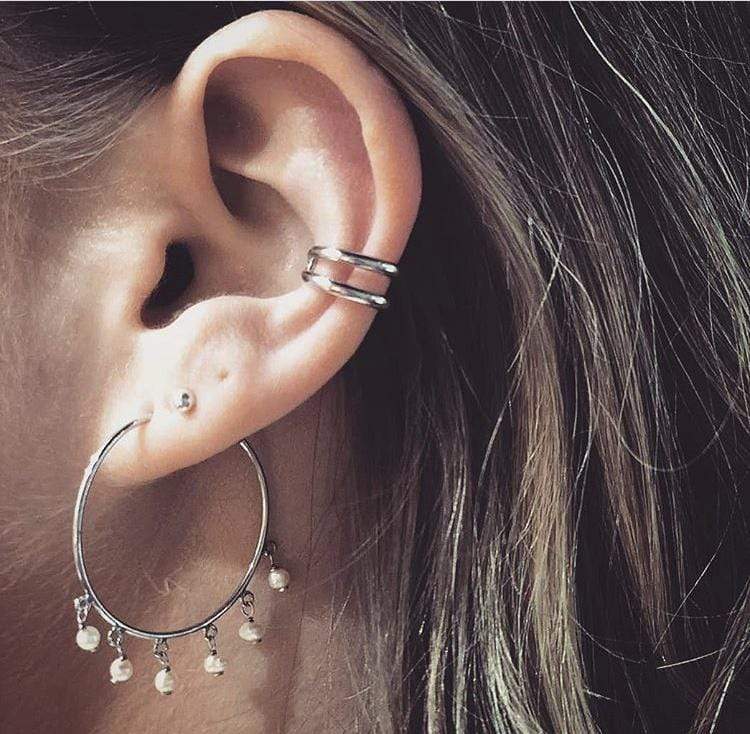 Delicate sterling silver ear cuff featuring parallel bars with a minimalist aesthetic, worn above a large hoop earring adorned with small hanging pearls.